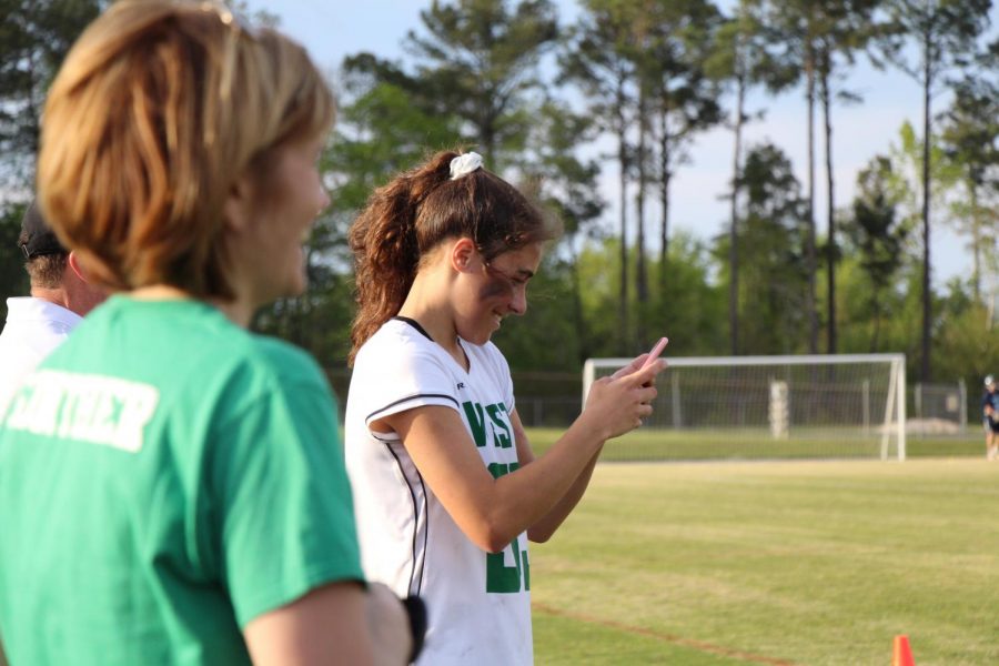 Cecelia Vergara stands off to the side as her fellow captains and teammates take the last photos of their high school lacrosse careers.