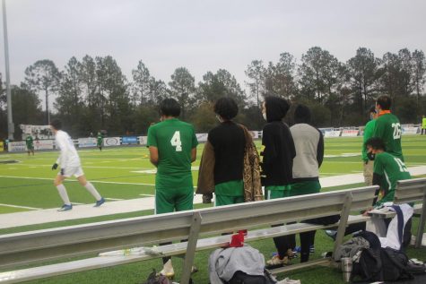 Teammates supporting their team on the sideline. 