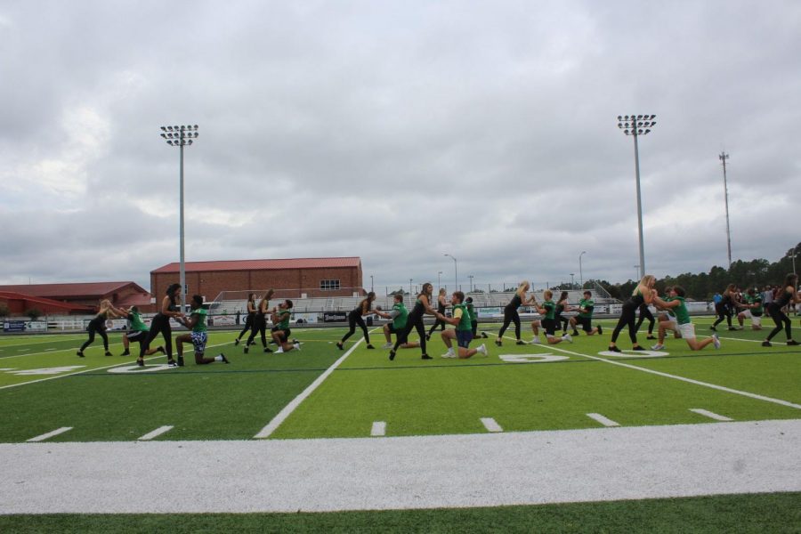 The dancers dance with the football team.