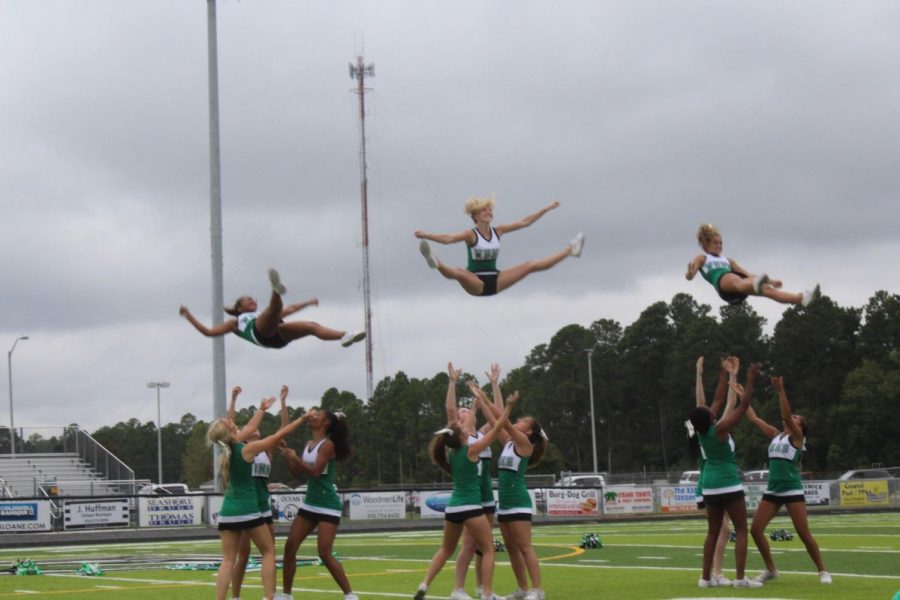 Three cheerleaders are thrown into the air while ready to be caught.