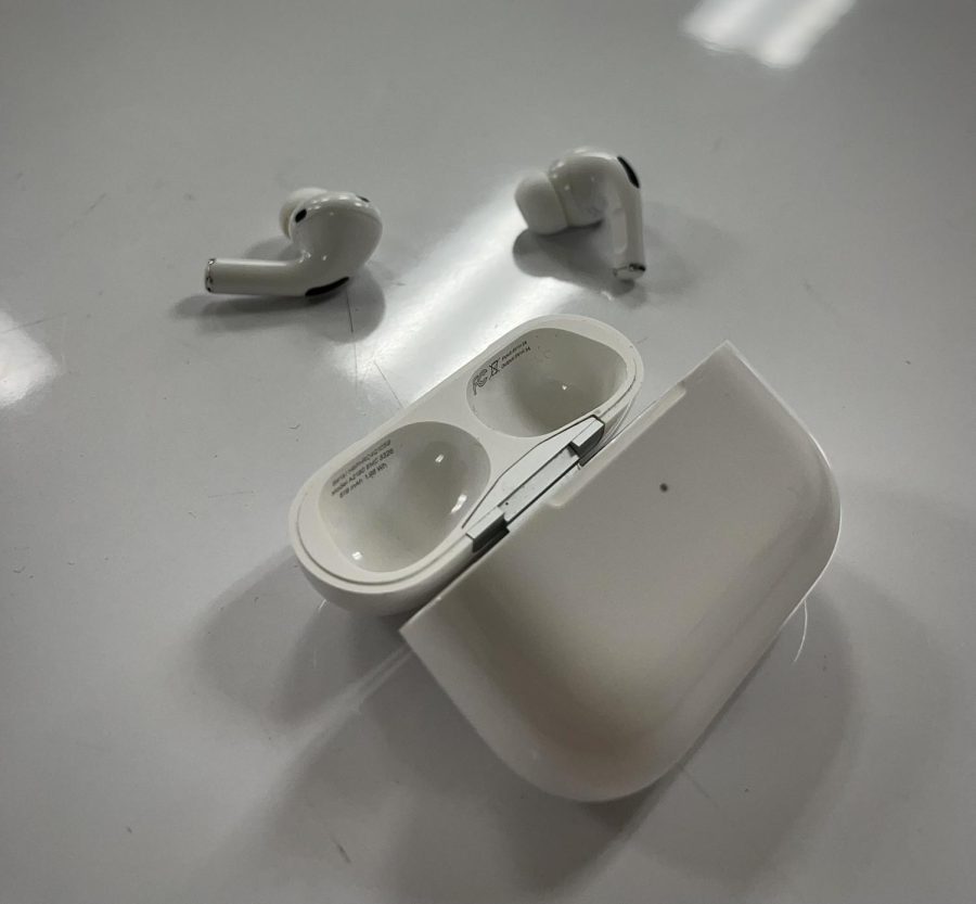 Airpod pros left unacknowledged on a desk.