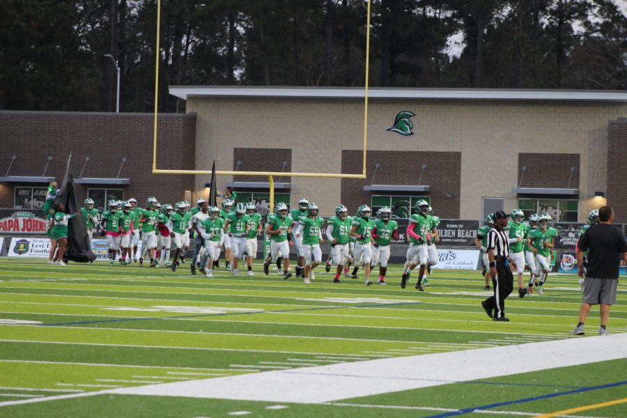 The junior varsity football and cheerleading teams run through the banner before the game. 