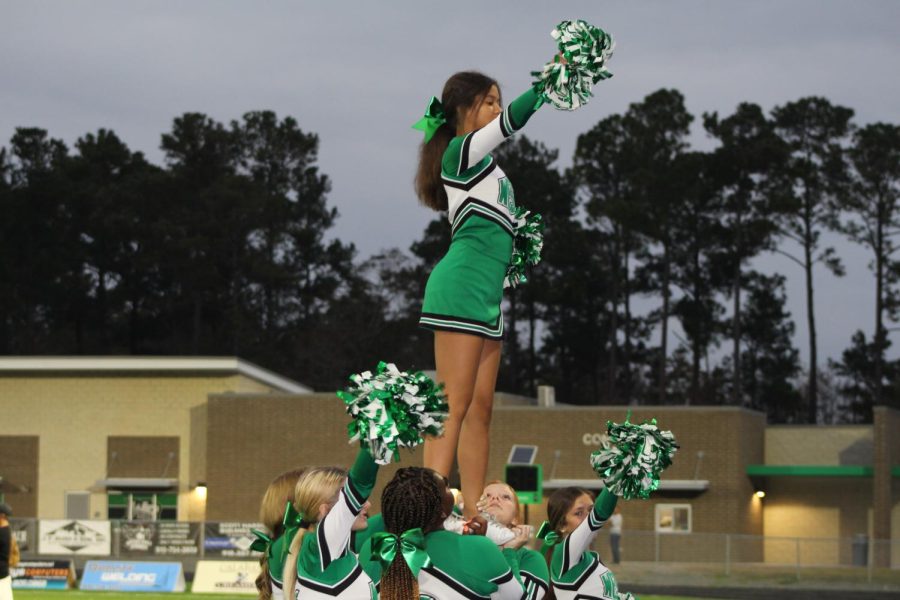 Cheerleaders in a stunt calling out a cheer for the players and fans.
