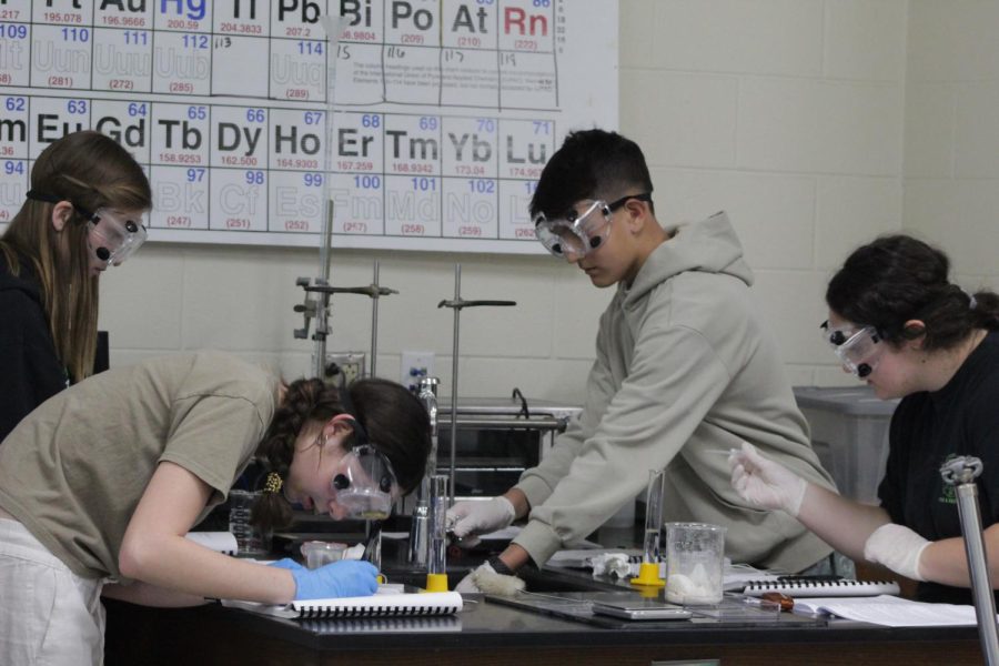 Lab group working together to record the temperature and measurements of the hydrochloric acid 