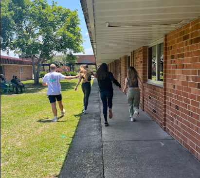 Noah Hewett, Amadis Levasa, Jayla Alejandro, and Kearstin Herring skipping down the side of the 100 building.