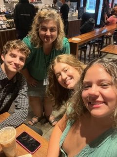 Crystal Karwacki, Anna Saunders, Courtney Weston, and Noah Farris posing for a selfie at Starbucks in preparation for a long last day at camp.