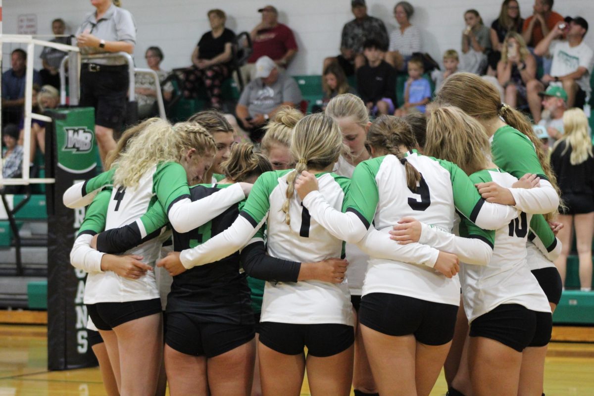 The+womens+varsity+volleyball+team+taking+a+moment+in+the+center+of+the+court+before+their+game+begins.
