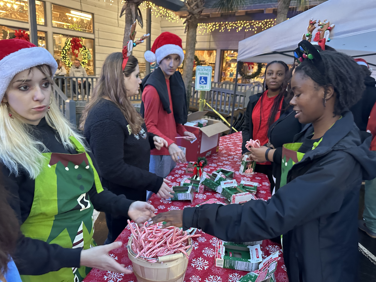Volunteers are opening candy canes to pass out throughout the parade to people who come to watch. 