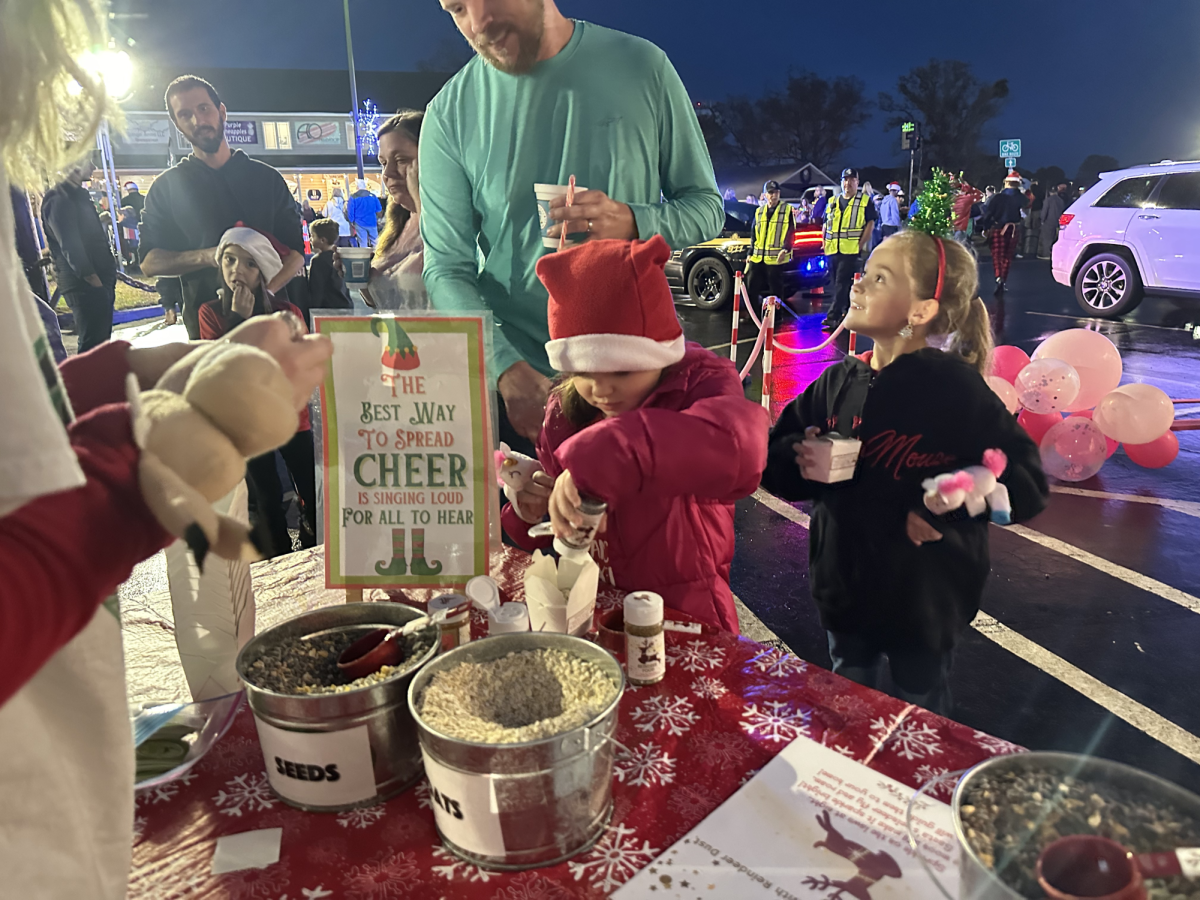 Kids and parents come up to the reindeer food station. Volunteers assist the kids and have lots of fun. 