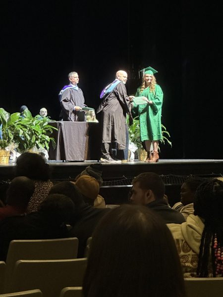 Principal Scott Dalton awarding an early graduate with her high school diploma.