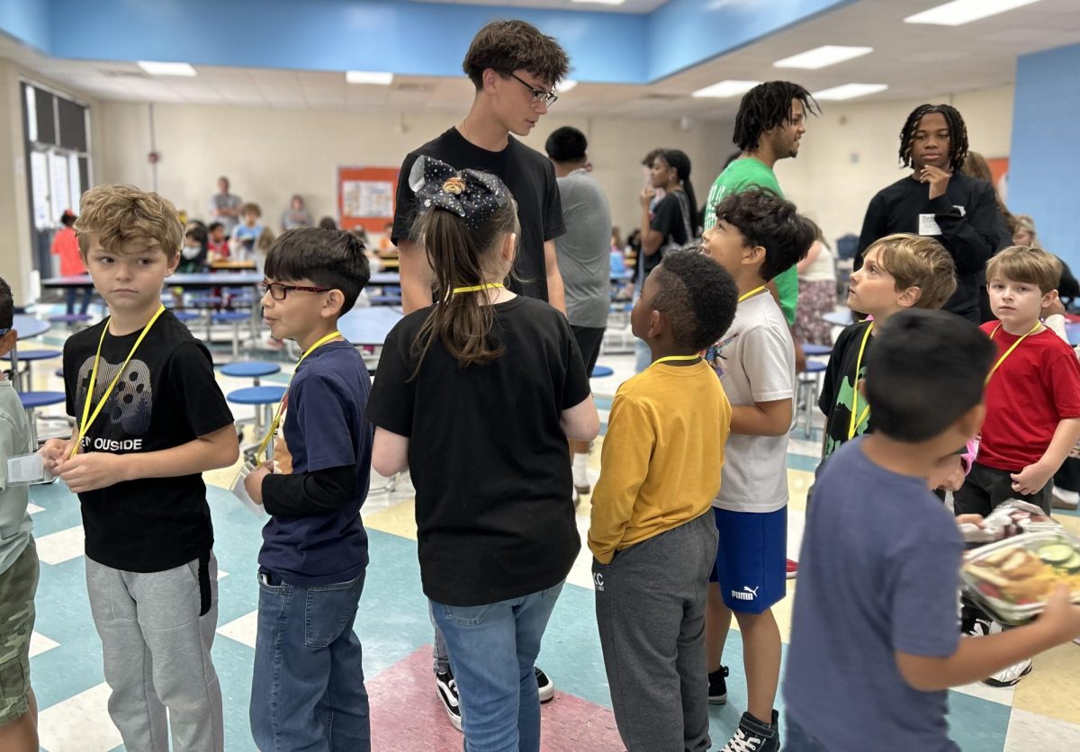 Junior Tucker Hamilton talks to a group of second graders waiting in the line for their lunch.