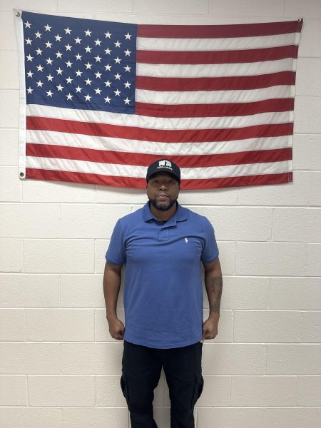 Chief Gause stands at attention Infront of the American flag with his West Brunswick hat on.