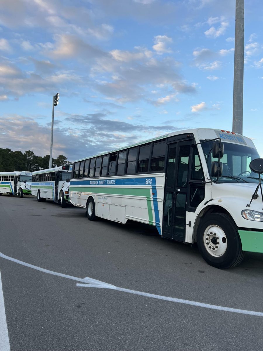 Activity buses line up beside the football field.