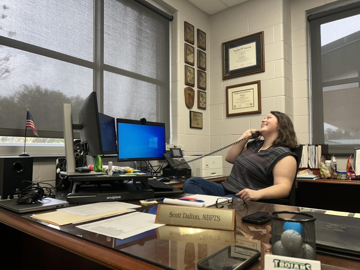 Hannah Underwood sits posing behind Principal Scott Dalton's desk. Pretending to be on the phone. 