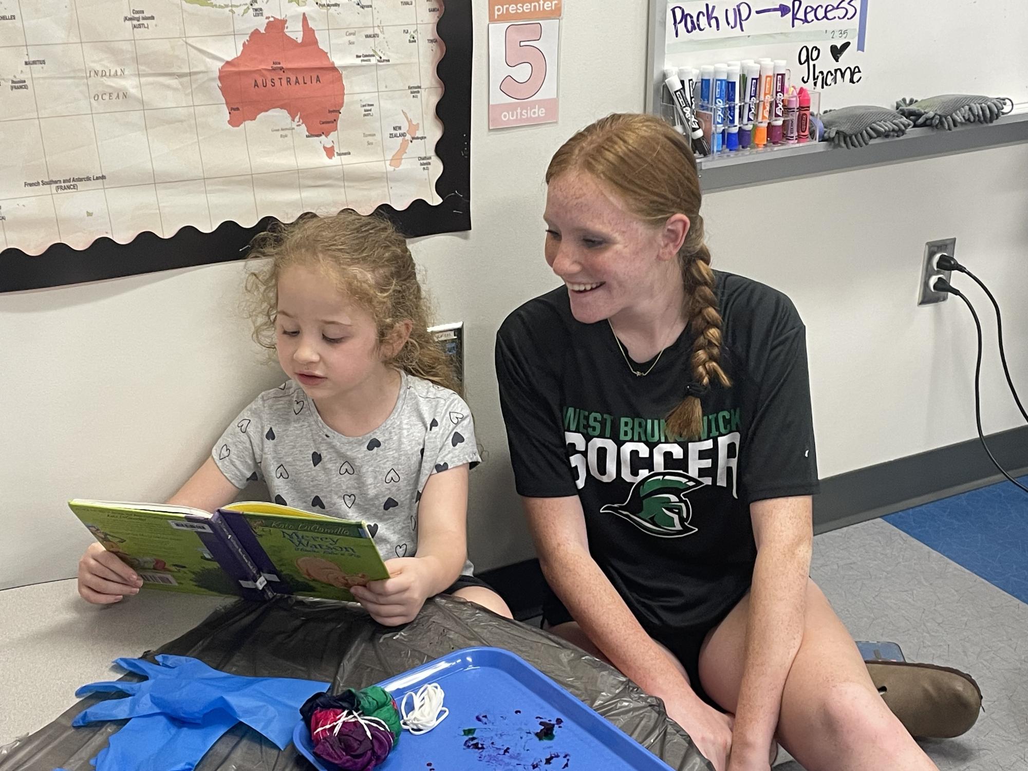 Junior Ava Tarman reading a book with her first grader. 