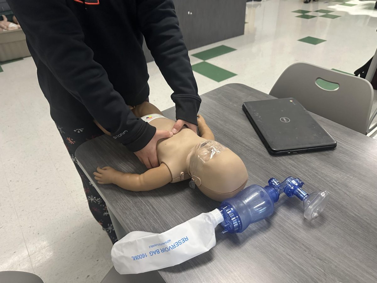 Junior Aniyaah Jacobs performing CPR on a baby manikin.